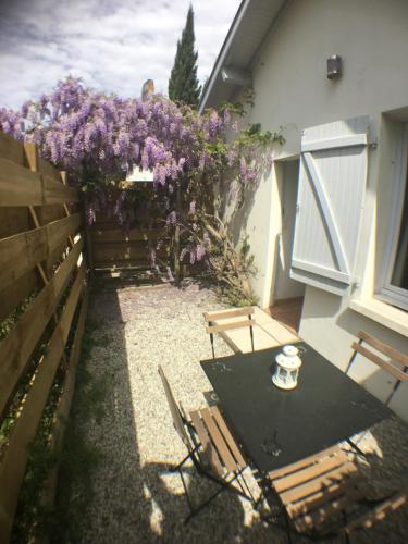 une table et des chaises à côté d'une clôture ornée de fleurs violettes dans l'établissement Maison T2, 4 étoiles, lac de Christus, à Saint-Paul-lès-Dax