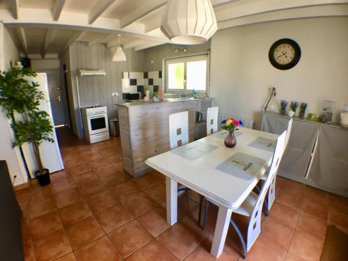 une cuisine avec une table blanche, des chaises et une horloge dans l'établissement Maison T2, 4 étoiles, lac de Christus, à Saint-Paul-lès-Dax