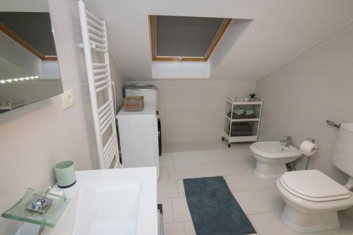 a white bathroom with a toilet and a sink at Apartment Skylight in Kostrena
