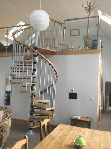 a spiral staircase in a living room with a table at Auld Skuil in Ashkirk