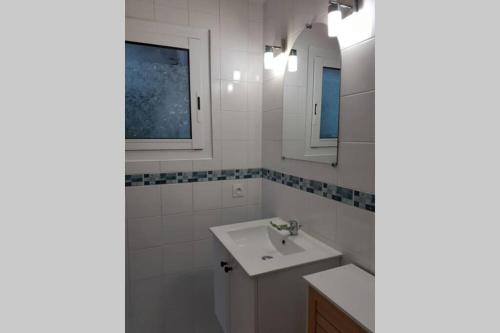 une salle de bain blanche avec un lavabo et un miroir dans l'établissement studio idéalement situé sur le Bassin d'Arcachon, à La Teste-de-Buch