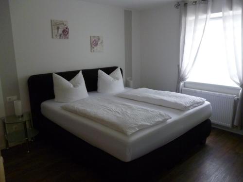 a bed with white sheets and pillows in a bedroom at Hotel Garni Reis in Treis-Karden
