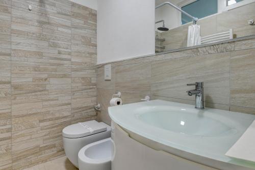 uma casa de banho com um lavatório branco e um WC. em My Desenzano Holiday Apartment em Desenzano del Garda