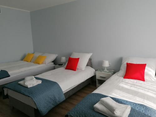 2 camas con almohadas rojas y amarillas en una habitación en Gladiator Noclegi Zator lV Apartament, en Zator