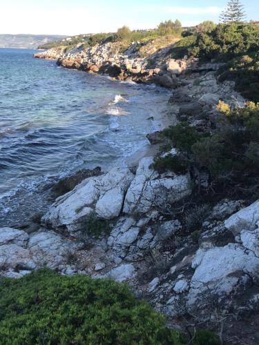 a rocky shoreline with the ocean and the water at Villa with swimming pool and tennis/basketball court in Theológos