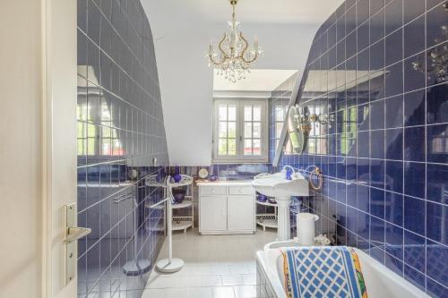 Ker Ys في Plonévez-Porzay: حمام من البلاط الأزرق مع حوض استحمام ومغسلة