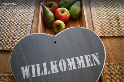 um sinal numa mesa com maçãs num cesto em Birkenblick Ferienwohnung Owwe em Rimbach