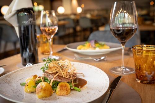 a table with a plate of food and a glass of wine at EUROPÄISCHER HOF Bad Gastein in Bad Gastein
