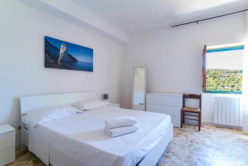 a white bedroom with a white bed and a chair at Casa Colletta Vieste in Vieste