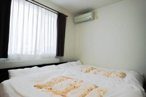 uma cama branca com duas almofadas e uma janela em STAY IN TOYOOKA em Asahikawa