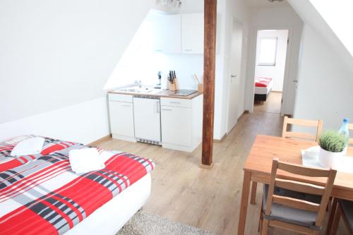 a bedroom with a bed and a table and a kitchen at Schwaben Apartment Plus in Oberboihingen
