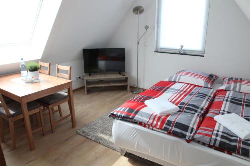 um quarto com uma cama, uma mesa e uma televisão em Schwaben Apartment Plus em Oberboihingen