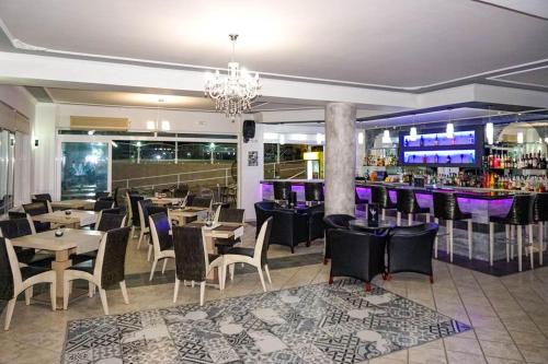 a restaurant with tables and chairs and a bar at Kerkyra Island Hotel in Mesongi