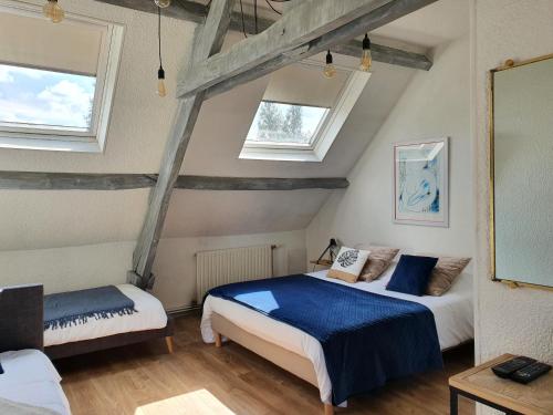 two beds in a room with two windows at Le Domaine d'Hérambault in Montcavrel