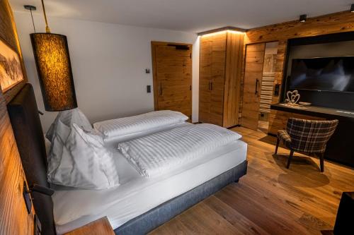 a bedroom with a large white bed and a television at DAS Hintersee in Hintersee