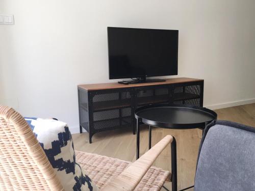 Casas Á Beira - Apartamentos في بونتيفيدرا: غرفة معيشة مع تلفزيون وطاولة وكراسي