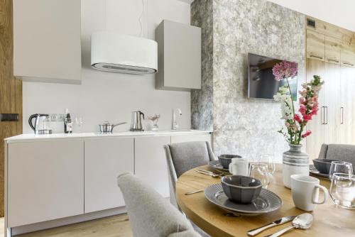 a kitchen with a wooden table and white cabinets at Tatra Resort & SPA in Kościelisko