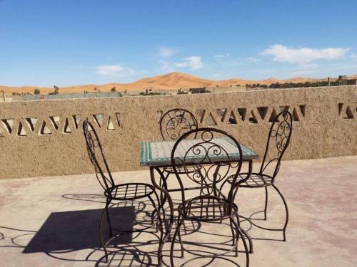 a table and chairs sitting in front of a wall at Riad Dar Poublanc in Merzouga