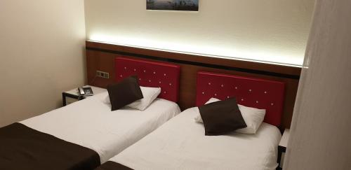 two beds in a hotel room with white and black pillows at Eriza Hotel in Erzincan