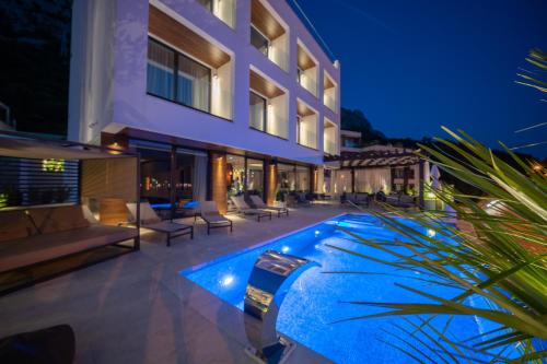 une villa avec une piscine la nuit dans l'établissement Boutique Hotel R Palazzo, à Kotor