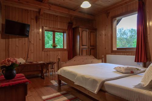 a bedroom with a bed and a table and a window at Pensiunea Poiana de Vis in Suceviţa