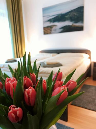 a vase of red tulips in front of a bed at Penzión Solisko*** Oščadnica in Oščadnica