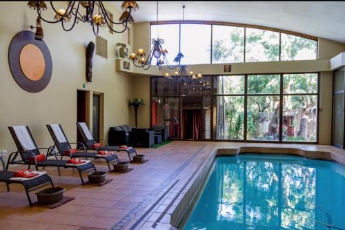 una piscina in una stanza con sedie e una grande finestra di Bloem Spa Hotel & Conference a Bloemfontein
