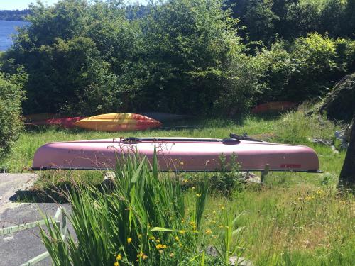 a boat sitting in the grass next to the water at Puget Sound Chic Romantic Cottage with Private Beach Access & Gated Entry in Port Ludlow