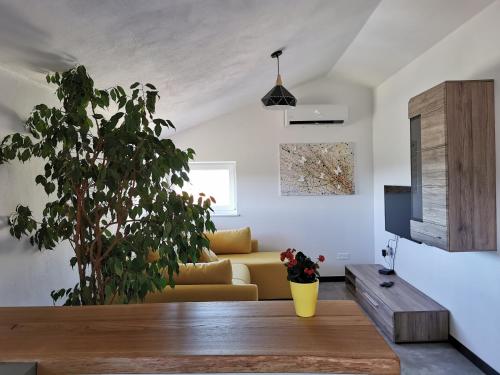 a living room with a yellow couch and a plant at Apartments Casa Tijola in Sečovlje