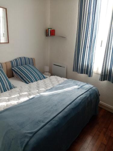 une chambre avec un lit avec des draps bleus et une fenêtre dans l'établissement Agréable appartement dans le vieux Trouville, à Trouville-sur-Mer