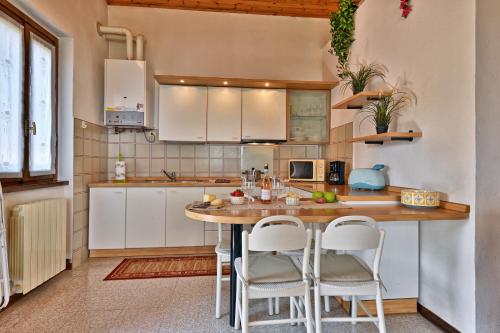 - une cuisine avec une table en bois et des placards blancs dans l'établissement Appartamento Mughetto - Rebomaholidays, à Tignale
