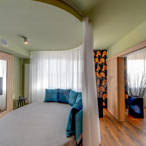 a bedroom with a large bed with blue pillows at Allure Healthy Hotel & Spa in Eger