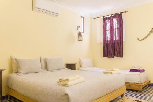 two beds in a room with towels on them at Medina social club in Fès