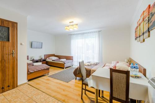 a room with a dining table and a living room at RAMZES USTKA -pokoje z balkonami, parking gratis ,rowery ,dobry dojazd do plazy i centrum in Ustka