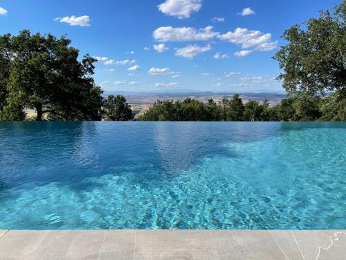 a swimming pool with blue water and trees in the background at BelSentiero in Campiglia dʼOrcia