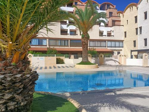 une piscine avec des palmiers devant un immeuble dans l'établissement Charmant Appartement vue PORT DE GRUISSAN 5DROM44K, à Gruissan
