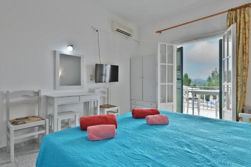 a bedroom with a blue bed with two red pillows at Fotini Studios in Paleokastritsa