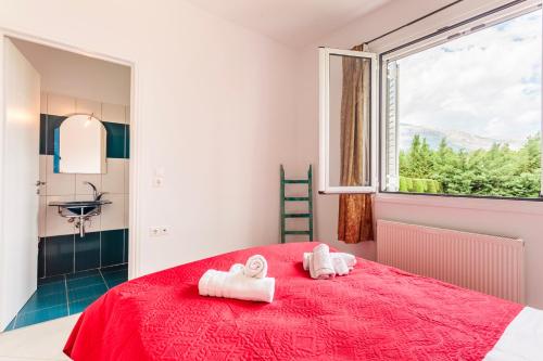 a bedroom with a red bed and a window at Villa Stymfalia - Luxury Mansion with Private Pool in Kartérion