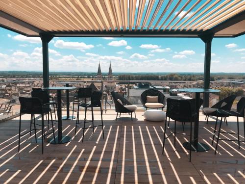 a patio with tables and chairs and a view of a city at HÔTEL & SPA Panorama 360 in Mâcon