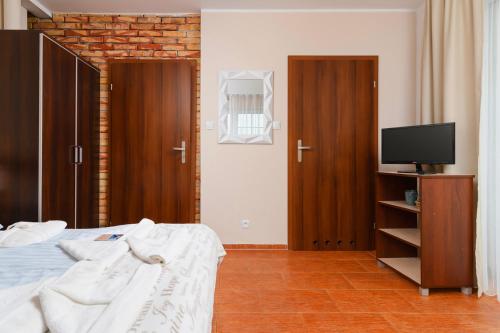 a bedroom with a bed and a tv and wooden doors at Villa Fenix in Ustronie Morskie
