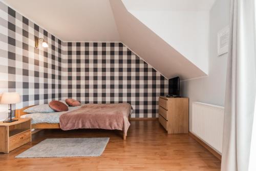 a bedroom with a bed and a black and white checkered wall at Domki i pokoje POD KOGUTEM - kwatery prywatne in Stegna