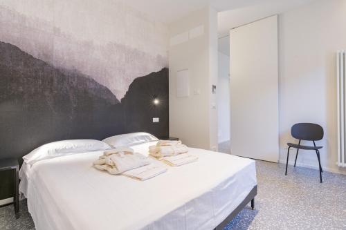 una camera da letto con un letto bianco e asciugamani di Domus la Scala a Verona