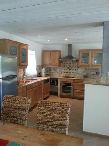 une cuisine avec des armoires en bois et un réfrigérateur en acier inoxydable dans l'établissement Sympathique Maison au Soleil & Whirlpool Privé dans Quartier Calme !, à Entrecasteaux