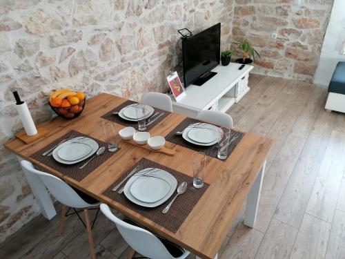 a wooden table with white plates and a television at Šimun&Jakov in Drinovci