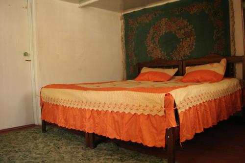 a bedroom with a bed with an orange comforter at Guest House Nazy in Stepantsminda