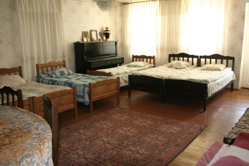 a room with three beds and a piano at Guest House Nazy in Stepantsminda