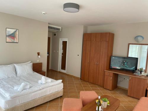 a living room with a white bed and a tv at Hotel ECO Palace in Primorsko