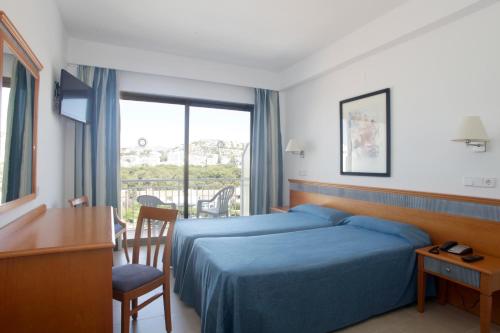 um quarto de hotel com uma cama, uma secretária e uma janela em Hotel Casablanca em Santa Ponsa