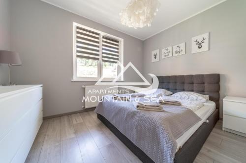 a bedroom with a bed and a chandelier at Apartament Grey in Szklarska Poręba