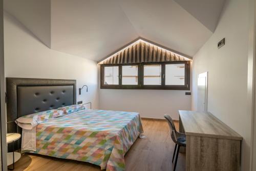 een slaapkamer met een bed, een tafel en een raam bij Casa Rural San Victorian 16 in Aínsa
